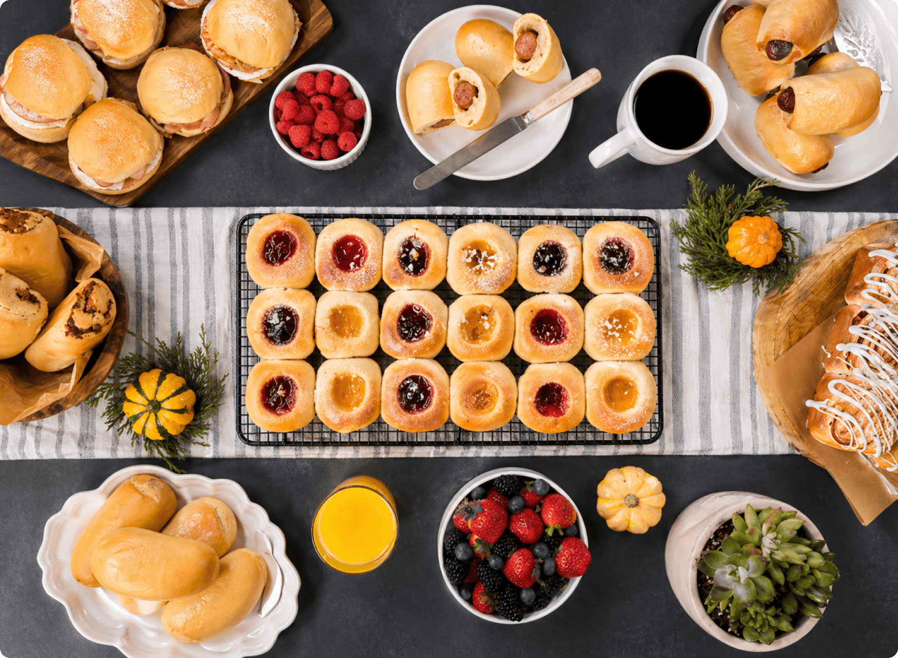 Catering spread of mini kolaches, fruit, and coffee on a slate-colored table