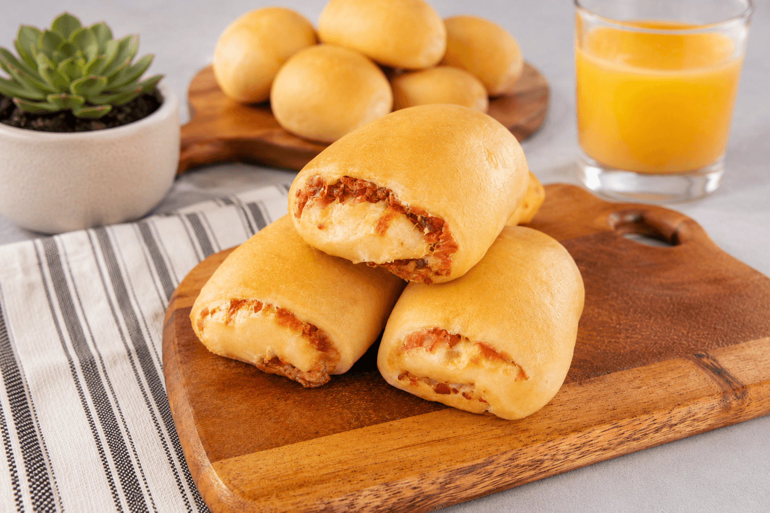 Fresh kolaches on a wooden serving board with orange juice